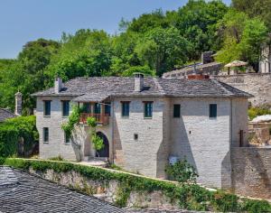 een oud stenen huis met een stenen muur bij Starry Land in Vitsa