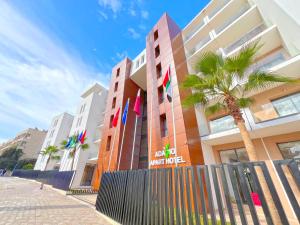 a building with a palm tree in front of it at Great Holiday suites in Agadir