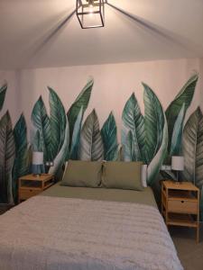 een slaapkamer met een grote muurschildering van bladeren aan de muur bij Arguineguín Heart in La Playa de Arguineguín