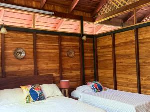 two beds in a room with wooden walls at Nicoya Silvestre in Lepanto