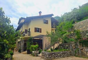 a large yellow house with a stone wall at Apartments Sandra in Lovran