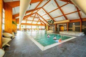 a large swimming pool with people in the water at Luxe Chalet Inn op de Veluwe aan het Water! in Otterlo