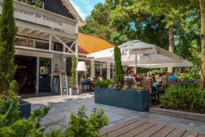 people sitting at an outdoor restaurant under umbrellas at Luxe Chalet Inn op de Veluwe aan het Water! in Otterlo