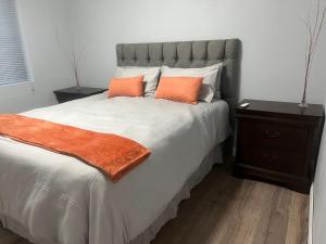 a bedroom with a large bed with two orange pillows at Oryx guest house in Oakdale