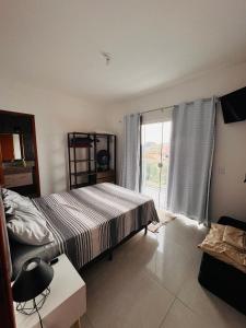 een slaapkamer met een bed en een groot raam bij Ap 800m da praia in Rio das Ostras