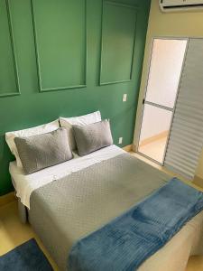 a bed in a room with a green wall at Flat Morada da Neblina! in Chapada dos Guimarães