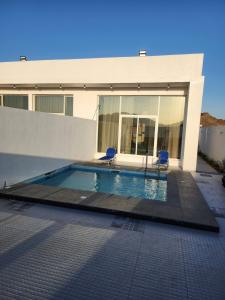 a swimming pool in front of a building with two chairs at Sun & moon in Būbādī