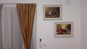 two pictures hanging on a wall next to a curtain at Aurora Lux in Vrnjačka Banja