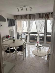 a living room with a table and chairs and windows at Résidence MAYA in Saint-Lary-Soulan