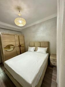 una camera da letto con un letto grande con lenzuola bianche di Monopolio gar tgv 5 min a Tangeri