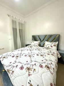 una camera da letto con un grande letto con un copriletto floreale di Monopolio gar tgv 5 min a Tangeri