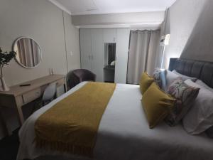a hotel room with a large bed with yellow pillows at 37 on Bell self catering accommodation in Harrismith
