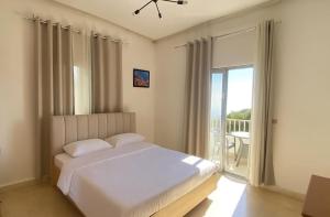 a bedroom with a white bed and a balcony at Zaaytre house in Ḩayy al Mukhabbaʼ