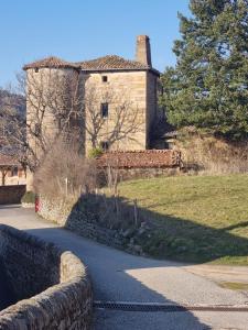 een gebouw met een stenen muur naast een weg bij Chez Marilou in Arcens