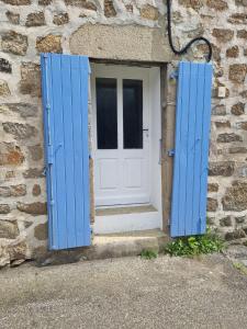 een deur met blauwe luiken op een stenen gebouw bij Chez Marilou in Arcens