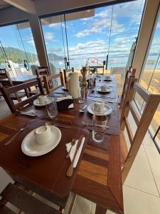 a wooden table with plates and glasses on top of a balcony at Casa Sol da Ilha in Angra dos Reis