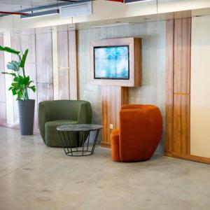 a lobby with two chairs and a table and a tv at Rainbow Residence Batumi in Batumi