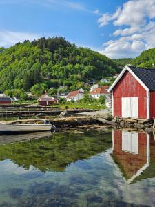 a red and white building and a boat in the water at FjordView Sanctuary in Nedstrand