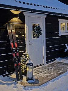 un paio di sci e una lanterna accanto a una porta di Mysig timmerstuga på dalagård a Leksand