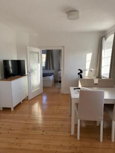 a white living room with a table and a television at Yellow House Apartments - Top 3 in Steyr