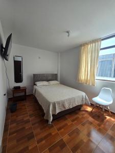 een slaapkamer met een bed, een stoel en een televisie bij Casa Wavve in Huanchaco