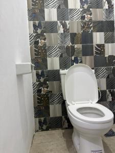 a bathroom with a toilet with a black and white wallpaper at Villa Blanche in Cotonou