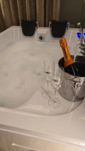 a bath tub with two glasses and a bottle of champagne at Delux Apartament z jacuzzi in Pszczyna
