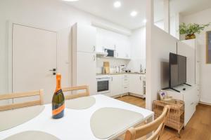 a white dining room with a bottle of wine on a table at Olomouc Central Apartment in Olomouc