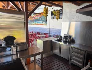 a kitchen with stainless steel appliances and a dining area at Hotel Kenito in São Tomé