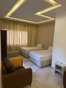 a hotel room with two beds and a couch at Hôtel Phoenicia in Brazzaville