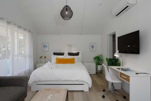 a white bedroom with a bed and a desk at Spacious, Breezy Studio Apartment, Moments from Downtown and Beach in Mount Maunganui