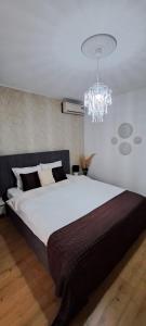 a bedroom with a large bed and a chandelier at Relax Apartament in Constanţa
