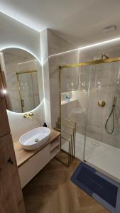 a bathroom with a sink and a shower at Delux Apartament z jacuzzi in Pszczyna