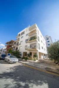 a white apartment building with a car parked in front of it at 2 bedroom flat in Strovolos