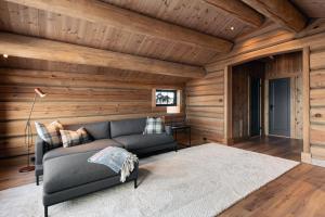 een woonkamer met een bank en houten wanden bij Nordic Gateway Logde in Hafjell