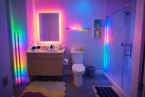 a bathroom with a toilet and a sink with rainbow lights at The Casa - U Street in Washington, D.C. +56 photos