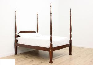 een hemelbed in een kamer met een houten vloer bij Les bungalows de la plage in La Trinité