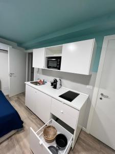 a small kitchen with white cabinets and a microwave at Residence della Accademia in Modena