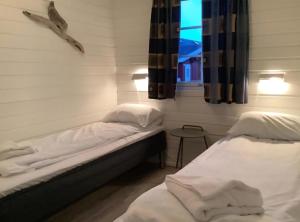 twee bedden in een kamer met een raam bij Ytterviks Rorbu Lofoten Welcome 欢迎 in Stamsund