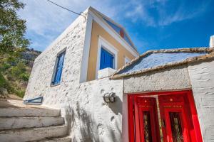 a white building with a red door and stairs at Symi Traditional Appartment in Symi +6 photos