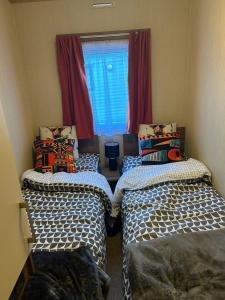 two beds in a room with a window at BZ Green Haven Caravan in Ballantrae