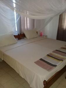 a large white bed with a canopy in a room at Diani Tembo One Bedroom in Mombasa