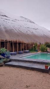 a building with a grass roof and a swimming pool at Cajanegra in El Cerrillo