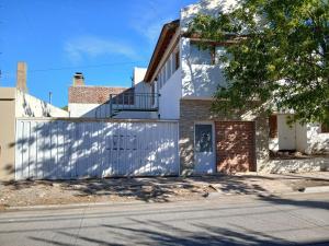 a white house with a gate and a garage at Franchesco apart familiar in Trelew