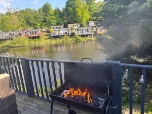 a barbecue on a deck next to a river at Dillons Lakeside Lodge in Caeathro