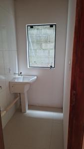 a white bathroom with a sink and a window at Aluguel diária in Florianópolis