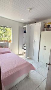 a white bedroom with a pink bed and a window at Bruna in Florianópolis