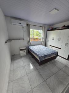 a bedroom with a bed and white cabinets and a window at Bruna in Florianópolis