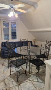a dining room table with chairs and a ceiling fan at Gite du bois des sapins in Groffliers