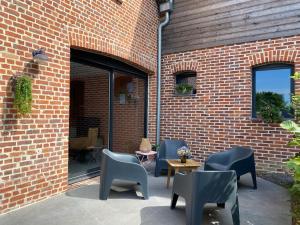 a patio with chairs and tables and a brick wall at Chez Aurel et Nico in Frélinghien